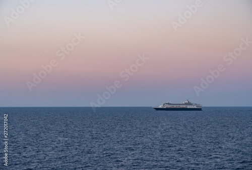 Small cruise liner sailing across the ocean as dawn starts to light the sky © steheap