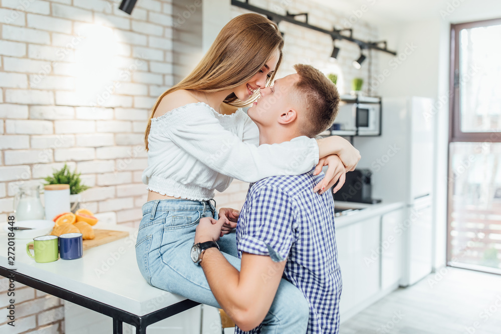 Happy loving couple kissing and hugging in the kitchen in the morning. Happy loving couple kissing and hugging in the kitchen in the morning.