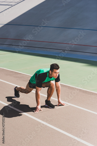 mixed race sportsman preparing to run at stadium © LIGHTFIELD STUDIOS