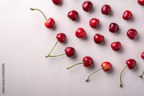 Copy space cherry berries with stem on wooden white background and water drops top view