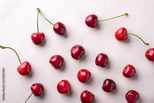 Copy space cherry berries with stem on wooden white background and water drops top view