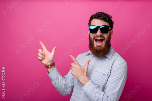 Portrait of amazed young man with beard pointing away at copyspace photo