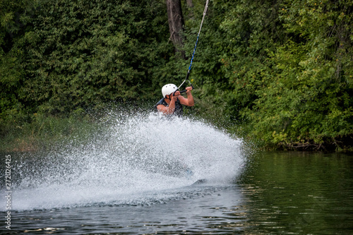 Man wakeboarding on river lake sea on summer spring day in jacket. Soft focus.