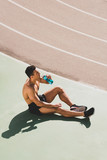 sportsman sitting at stadium and drinking water