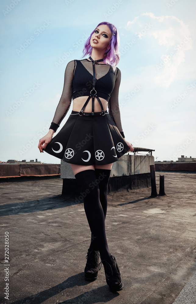 Portrait of lovely gothic girl on roof. Pastel goth with violet (pink) hair  in black clothes ภาพถ่ายสต็อก