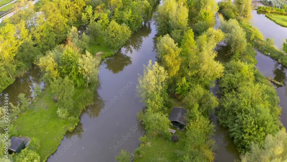 Aerial reveal from top down of the Netherlands countryside, cottages on islands within rivers and forest contrasted with farmland. Birds circle around the drone Aerial reveal from top down of the Netherlands countryside, cottages on islands within rivers and forest contrasted with farmland. Birds circle around the drone