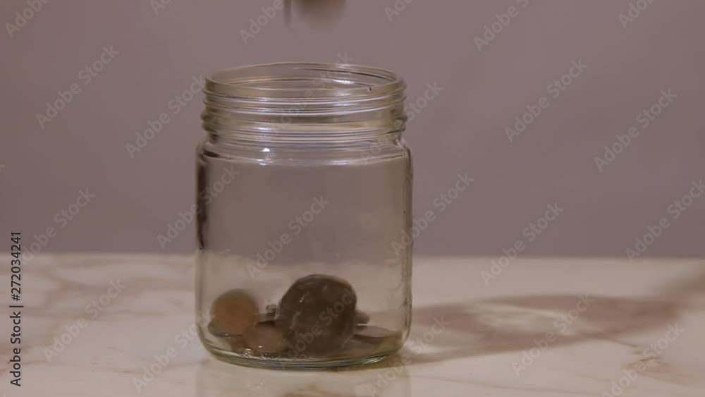 Loose change dropping slowly in a jar. Loose change dropping slowly in a jar.
