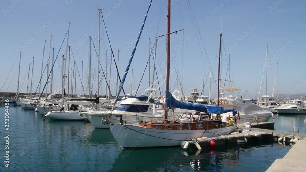 White boats, yachts, and sailboats docked in calm blue harbor White boats, yachts, and sailboats docked in calm blue harbor