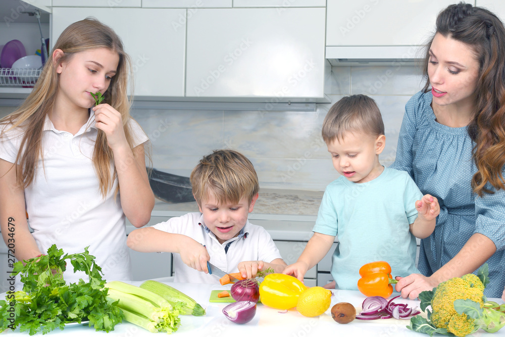 family with children cut vegetables for cooking.