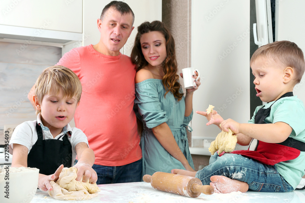 little boys knead the dough on the background of their parents.