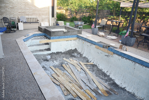 Valokuva Empty swimming pool under remodel with new tile and coping with wooden debris