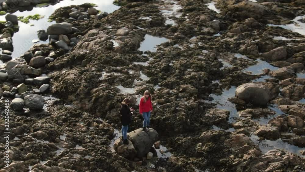 Two girls in Ireland climb over the rocky oceanfront of Malin Head - travel photography Two girls in Ireland climb over the rocky oceanfront of Malin Head - travel photography