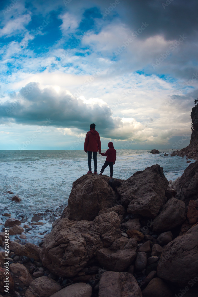 Silhouette of a woman and a child against the sea and sky.