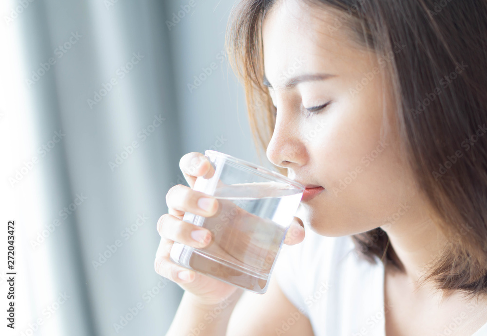 Close up woman drinking pure water from glass with light in the morning, Selective focus Close up woman drinking pure water from glass with light in the morning, Selective focus