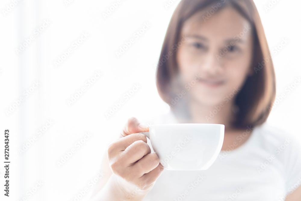 Closeup woman holding a cup of hot coffee with over light from window, selective focus Closeup woman holding a cup of hot coffee with over light from window, selective focus