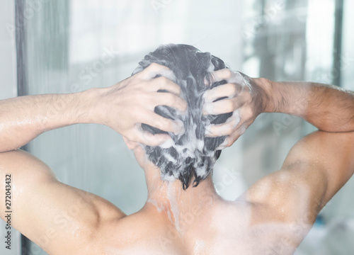 Φωτογραφία Closeup young man washing hair with with shampoo in the bathroom, vintage tone,