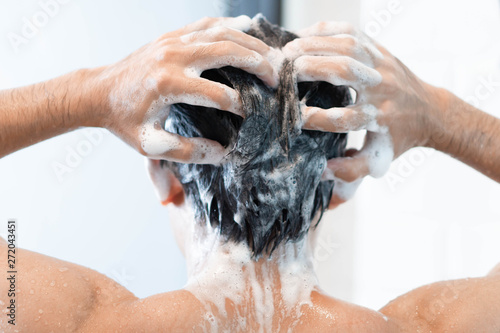 Tableau sur toile Closeup young man washing hair with with shampoo in the bathroom, health care co
