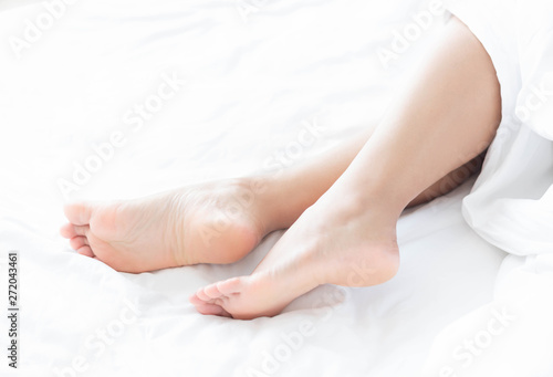 Closeup woman feet relaxing and happy time on white bed, beauty and health care concept