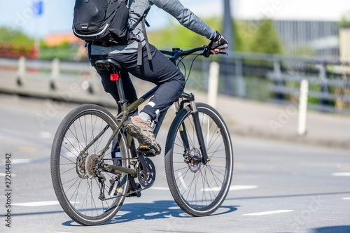 Fototapeta Naklejka Na Ścianę i Meble -  Cyclist with backpack lover of active lifestyle rides bike on city street