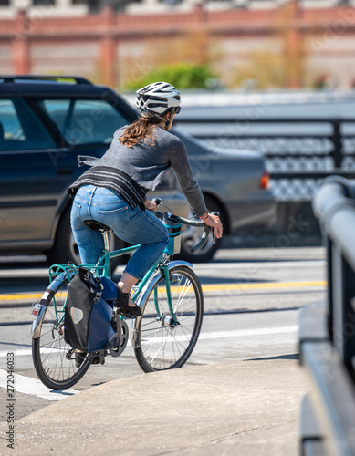 Woman cyclist in helmet rides bicycle on the streets of the urban city © vit