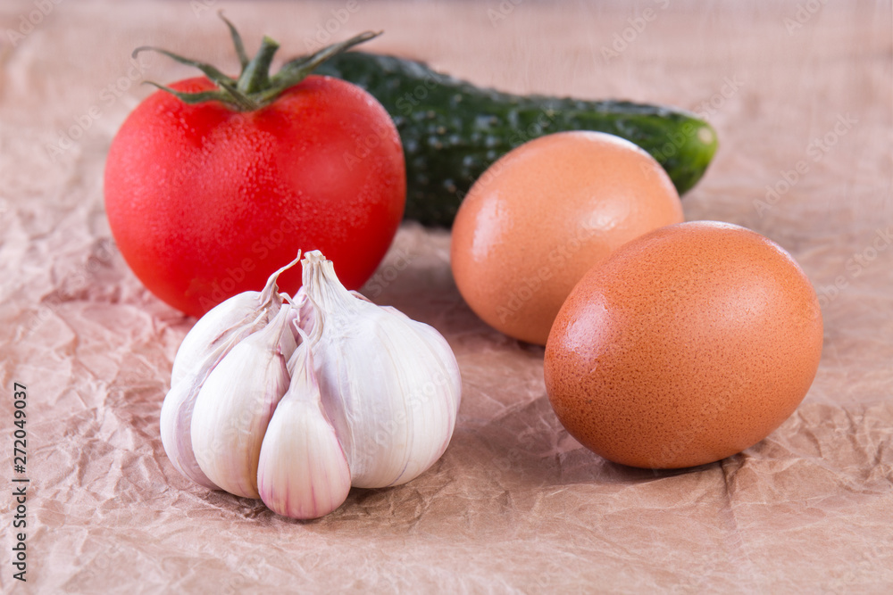 Vegetables still life. ucumber, garlic, eggs and tomato. rumpled paper background. close-up Vegetables still life. ucumber, garlic, eggs and tomato. rumpled paper background. close-up