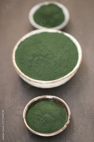 Spirulina algae. dry powder in round cups set on a black table.organic spirulina algae powder.Super food concept.nutritional supplement.