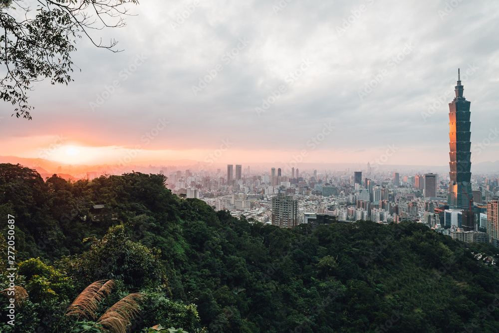 Aerial panorama over Downtown Taipei with Taipei 101 Skyscraper with trees on mountain in foreground in the dusk from Xiangshan Elephant Mountain in the evening. Aerial panorama over Downtown Taipei with Taipei 101 Skyscraper with trees on mountain in foreground in the dusk from Xiangshan Elephant Mountain in the evening.