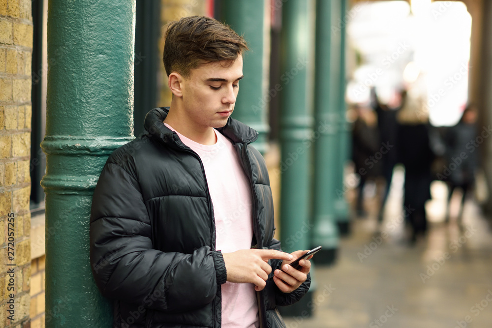 Young urban man using smartphone in urban background. Young urban man using smartphone in urban background.