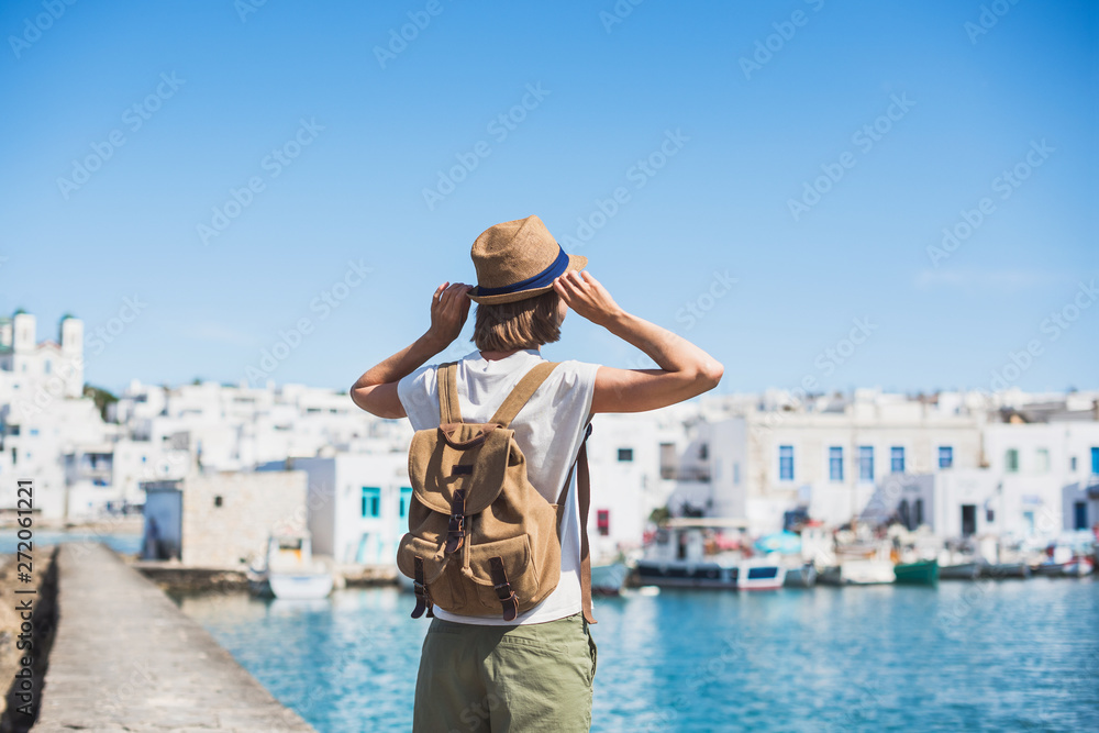 Obraz premium Dziewczyna podróżnik korzystających z wakacji w Grecji. Młoda kobieta w kapeluszu patrząc na grecką wioskę z morzem. Wakacje letnie, wakacje, podróże, koncepcja turystyki.