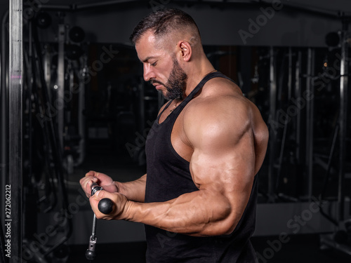  Bodybuilder in the gym. Sports photo shoot. Man's fitness. Training and exercises with dumbbells. Men's photo shoot in low key. Athletic build. young man lifting weights in gym