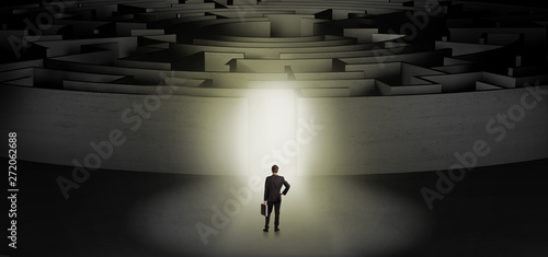 Businessman getting ready to enter a concentric labyrinth with lighted entrance concept 