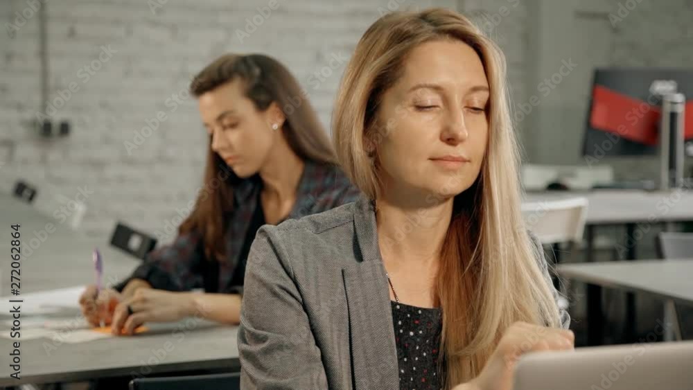 Two woman sitting behind desk table and working in office Two woman sitting behind desk table and working in office