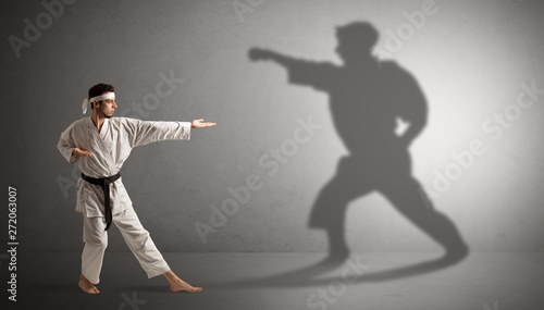 Young karate man confronting with his own shadow 