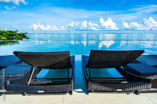 Umbrella and chair around swimming pool in hotel resort neary sea ocean beach for leisure relax in holiday