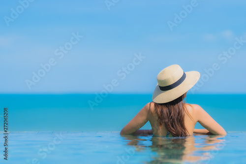 Portrait beautiful young asian woman happy smile relax in swimming pool at hotel resort neary sea ocean beach on blue sky