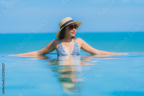 Portrait beautiful young asian woman happy smile relax in swimming pool at hotel resort neary sea ocean beach on blue sky