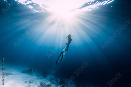 Photographie Woman freediver glides over sandy sea with fins
