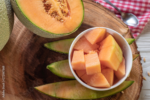 Fresh of whole orange melon or cantaloupe and cut intp pieces on background wooden table. Favorite fruit in summer concept. photo