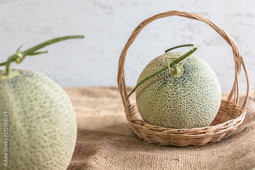Fresh of whole orange melon or cantaloupe on burlap fabric sack background and wooden table. Favorite fruit in summer concept. . The family of Cucurbitaceae.