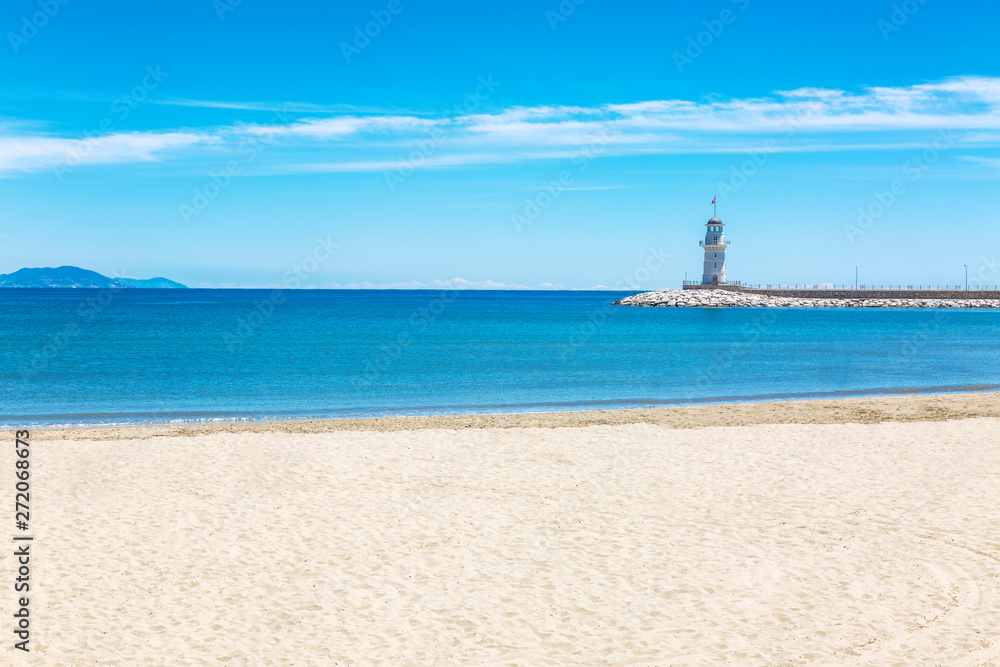 Fototapeta premium Beautiful view of the lighthouse in the sea from the beach. Space for text.