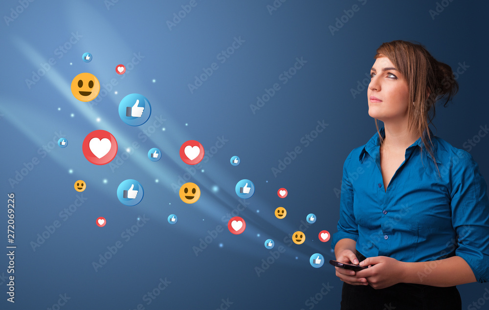 Fototapeta premium Young person using smartphone with flying social media icons around 