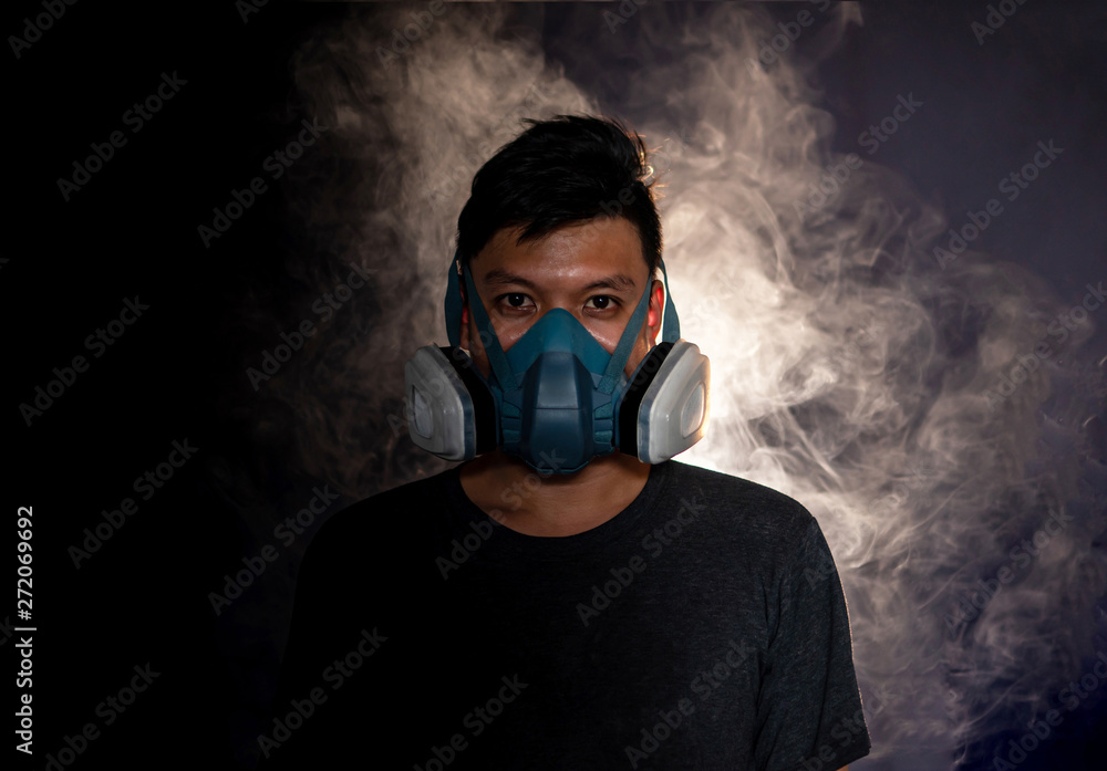 man in a gas mask smokes and breathes a cloud of tobacco smoke ,black background man in a gas mask smokes and breathes a cloud of tobacco smoke ,black background