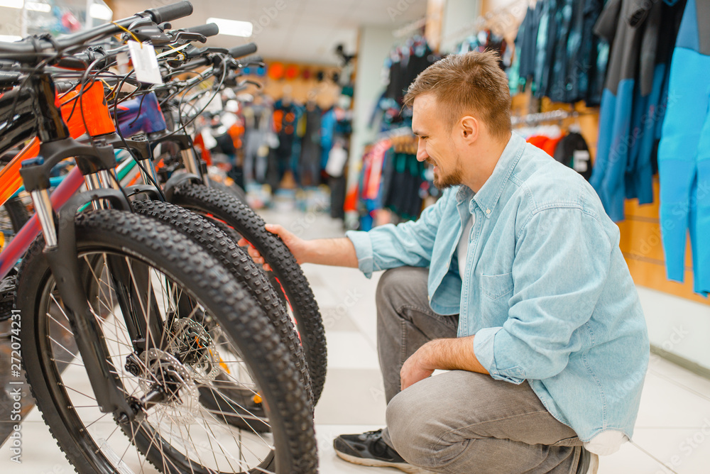Obraz premium Man checks bicycle tyre, shopping in sports shop