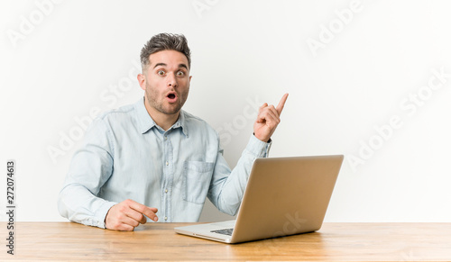 Young handsome man working with his laptop pointing to the side