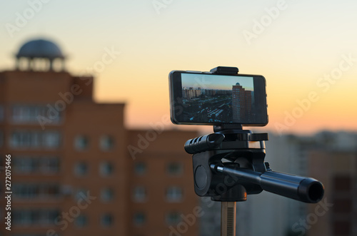 smartphone, fixed on a tripod, takes a picture of the city during sunset without human intervention