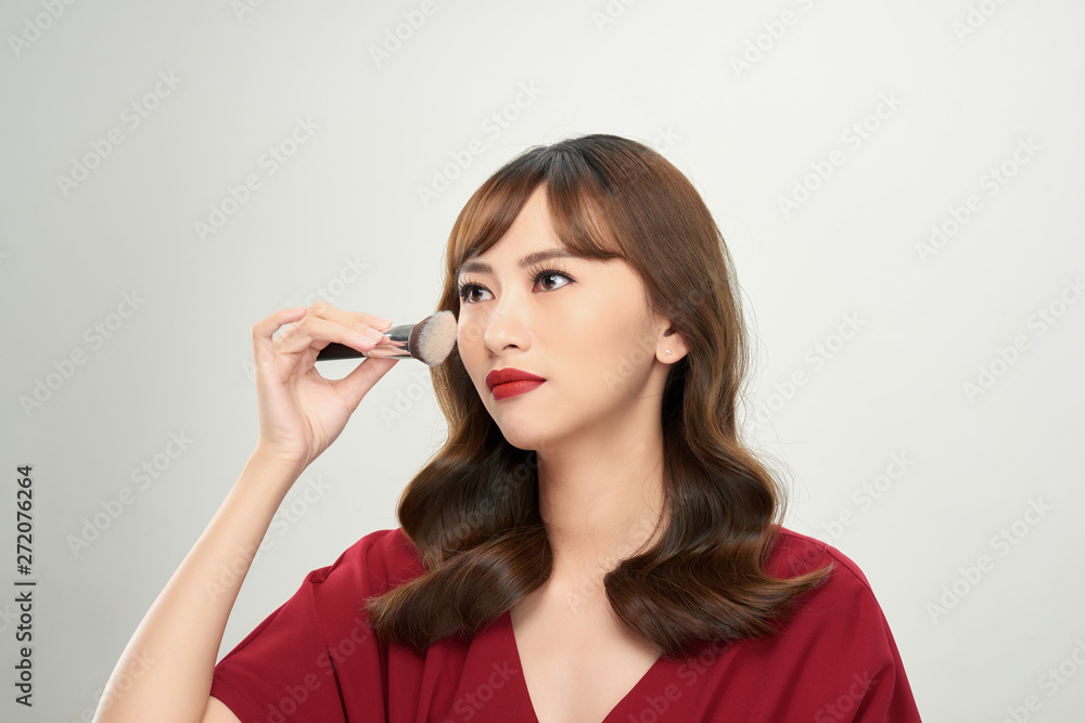 Beautiful young woman applying foundation powder or blush with makeup brush Beautiful young woman applying foundation powder or blush with makeup brush