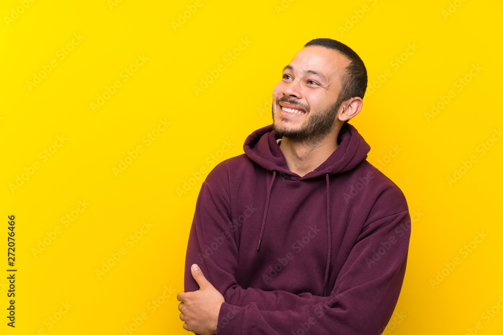 Colombian man with sweatshirt over yellow wall happy and smiling Colombian man with sweatshirt over yellow wall happy and smiling