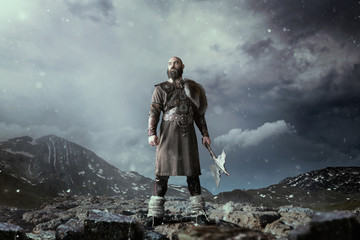 Viking with axe standing in rocky mountains