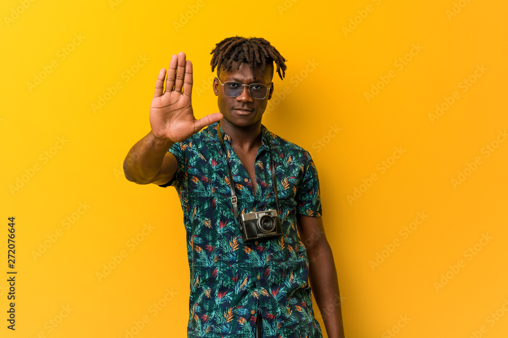 Young black rasta man wearing a vacation look standing with outstretched hand showing stop sign, preventing you. Young black rasta man wearing a vacation look standing with outstretched hand showing stop sign, preventing you.