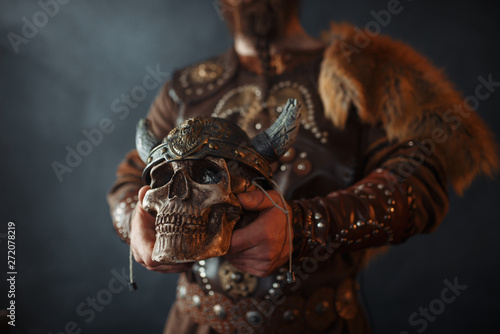Viking holds human skull in helmet